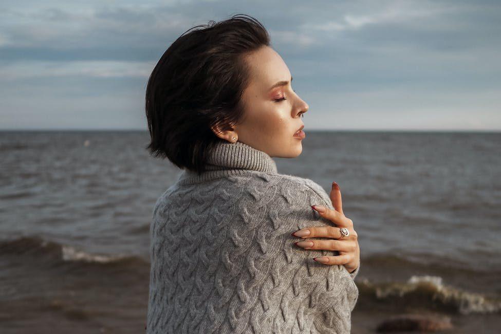 woman hugging herself on a seashore, illustrating emotional resilience through mindfulness techniques