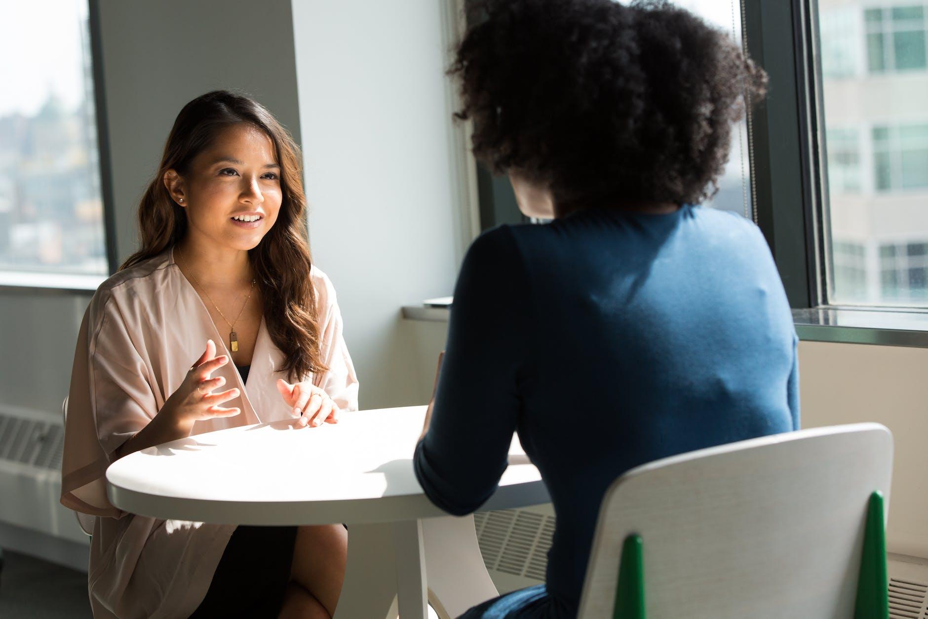 two women chatting at a table, illustrating the benefits of mindfulness for wellbeing in relationships 