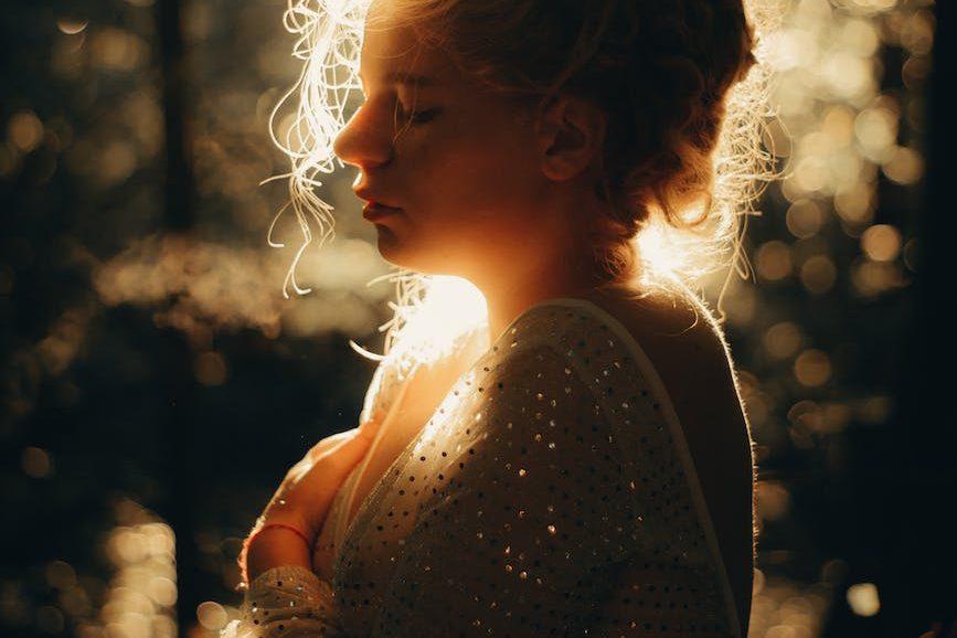 back lit profile of a girl wearing a vintage dress in a park, illustrating mindfulness techniques