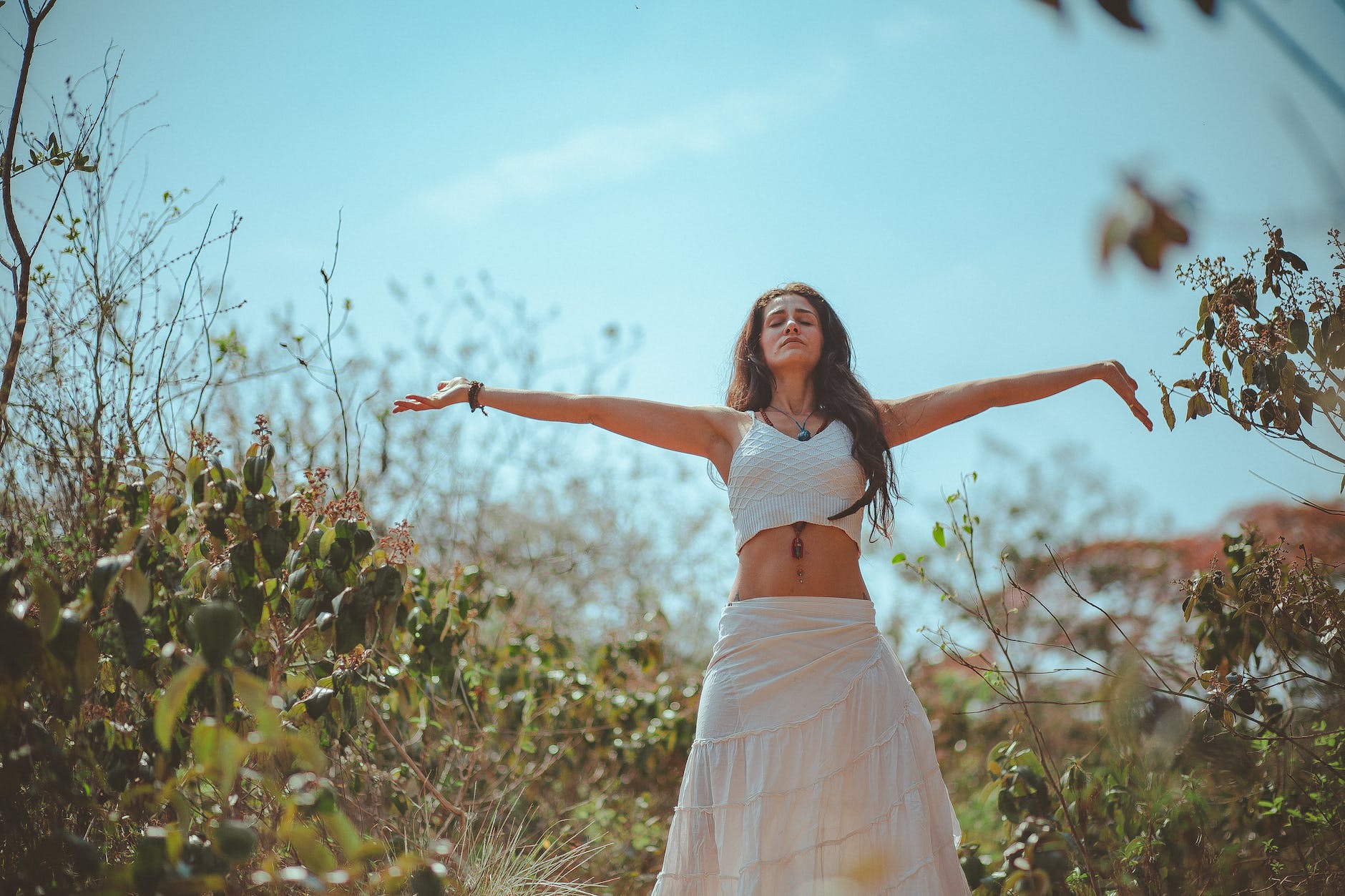 woman spreading both her arms in nature, practicing daily mindfulness for personal awareness, emotional healing, and self-care