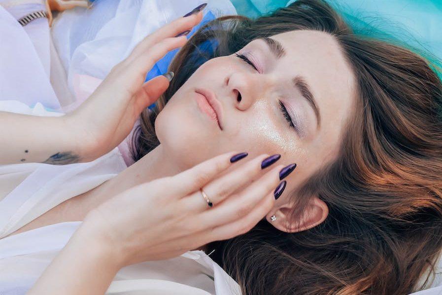 woman in white top lying on assorted color textiles, practicing daily mindfulness for self-care and self-compassion