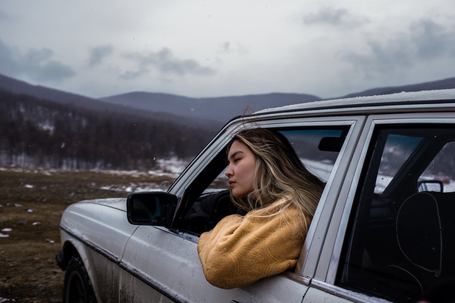 woman in brown sweater sitting inside car, illustrating emotional balance from meditation for stress relief