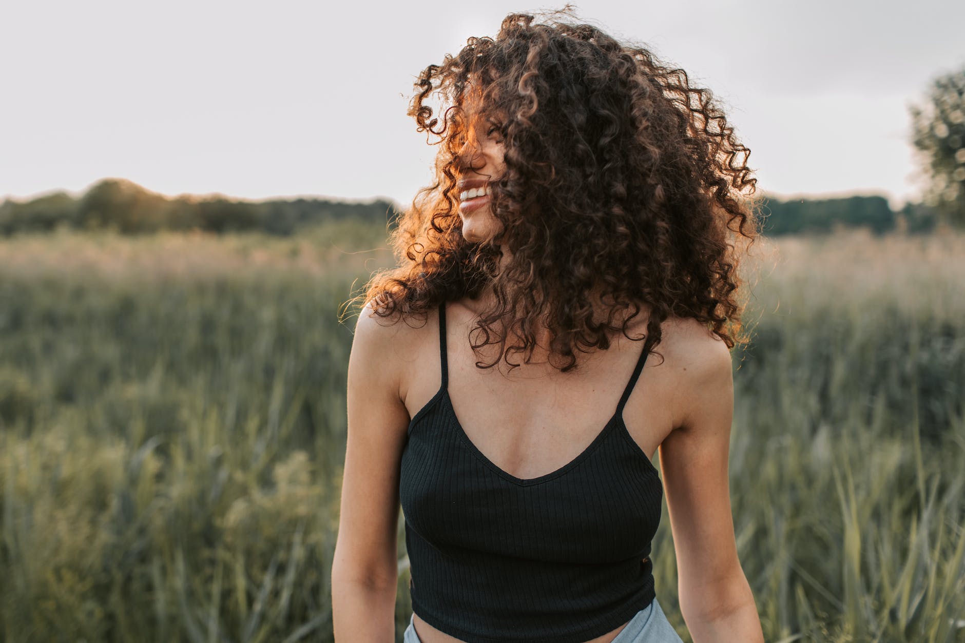 photo of woman wearing black tank top in a field, illustrating the versitility of mindfulness techniques for self-empowerment and awareness