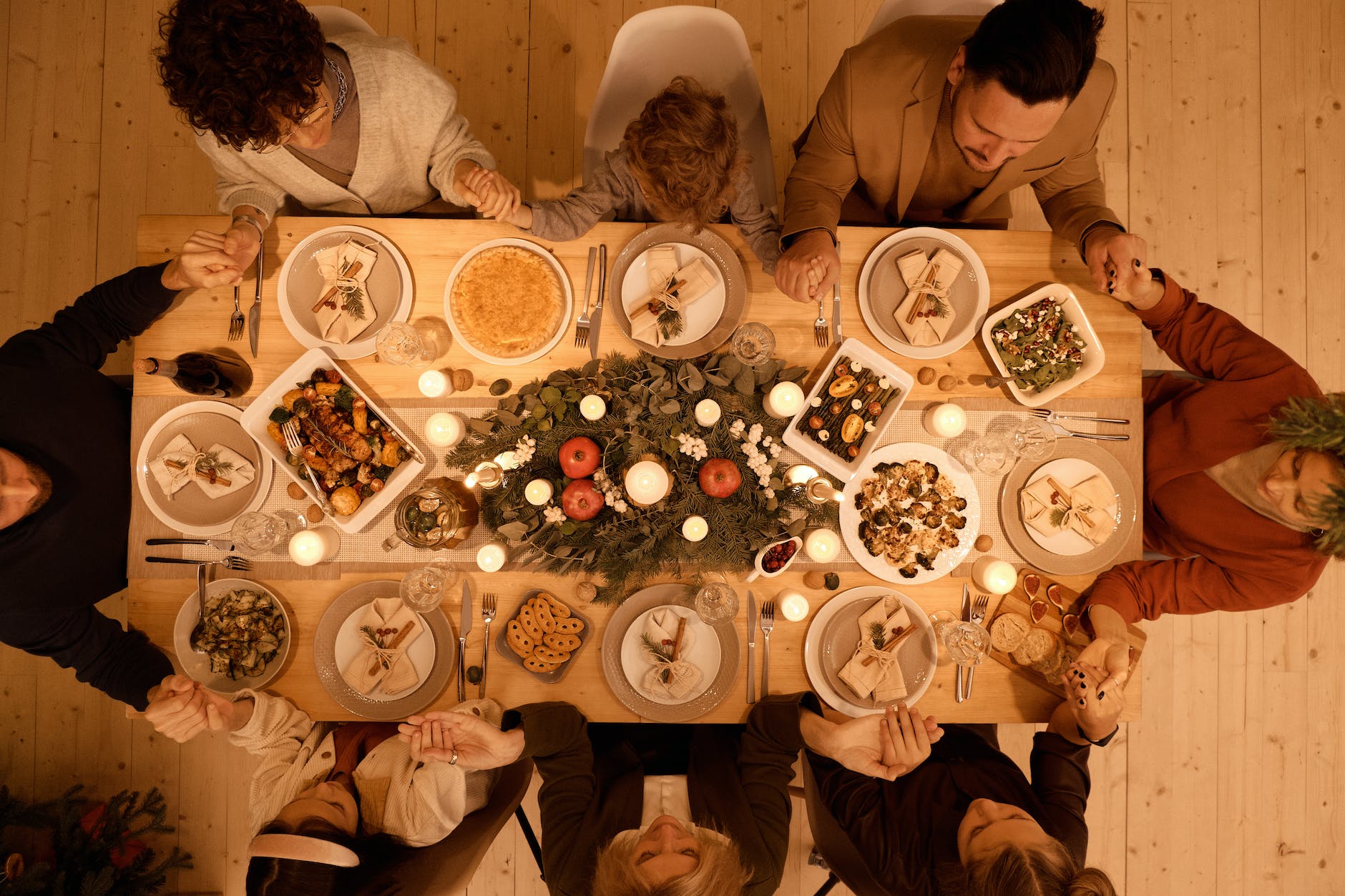 top view of a family praying before dinner, for Lughnasadh, first harvest, abundance festivals, to celebrate harvest and honor seasonal traditions