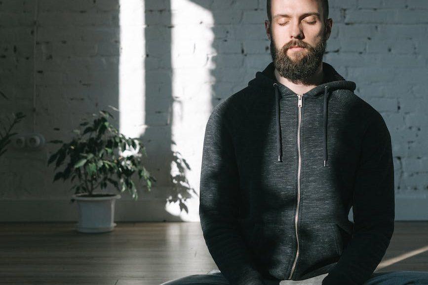 a man sitting in yoga mat in mindful meditation practice, illustrating a daily meditation routine