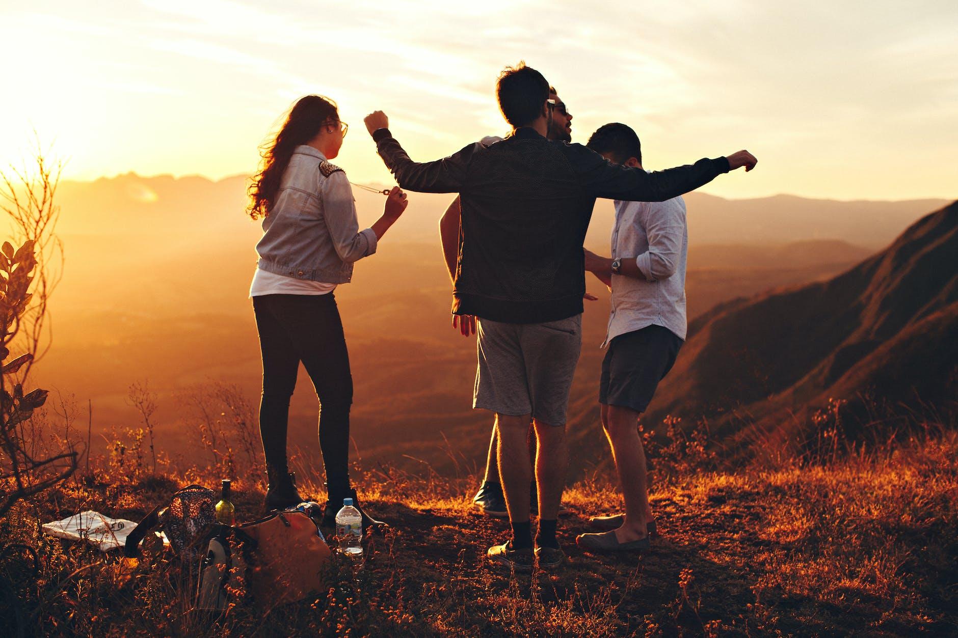 four person standing at top of grassy mountain, exploring types of meditation and meditation techniques, as well as the benefits of meditation, mindfulness meditation, and how to meditate