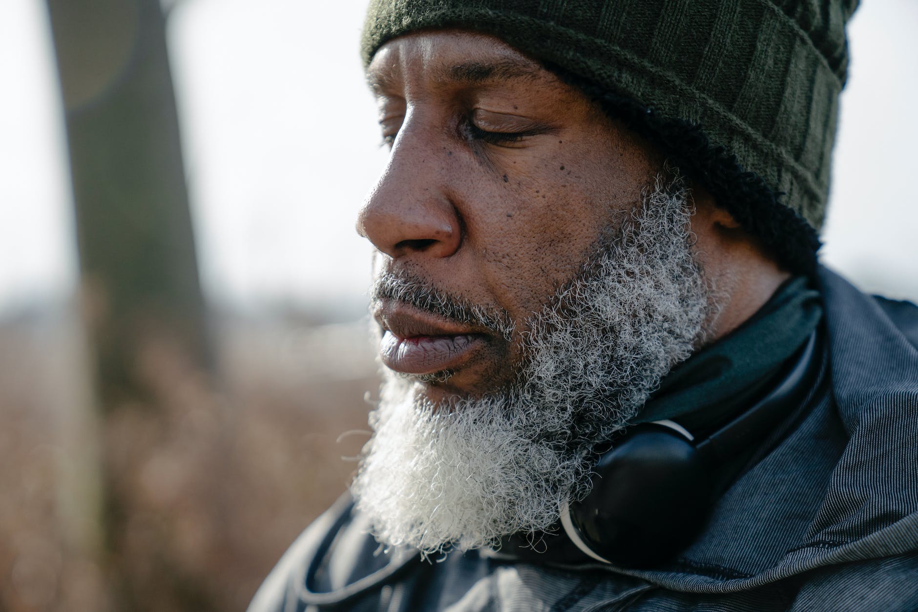 serious bearded black man in warm clothes with closed eyes, practicing daily mindfulness for self-care