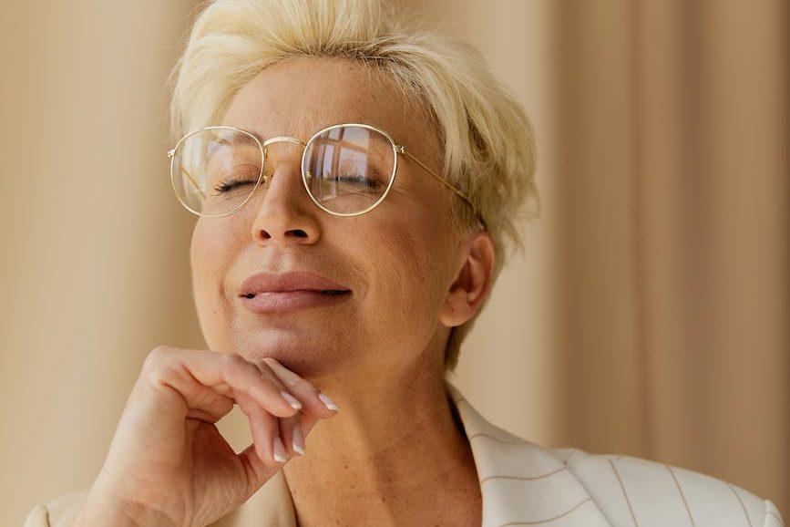 professional woman wearing eyeglasses, smiling and enjoying mindfulness for wellbeing, self-empowerment, and awareness