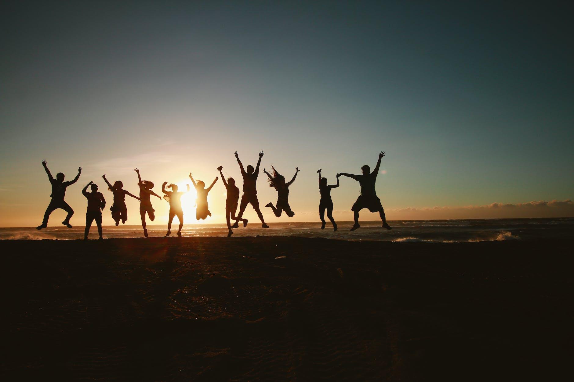 silhouette photography of group of people jumping during golden time, showing the importance of interconnectedness, meditation, oneness, unity and compassion, and connection with nature