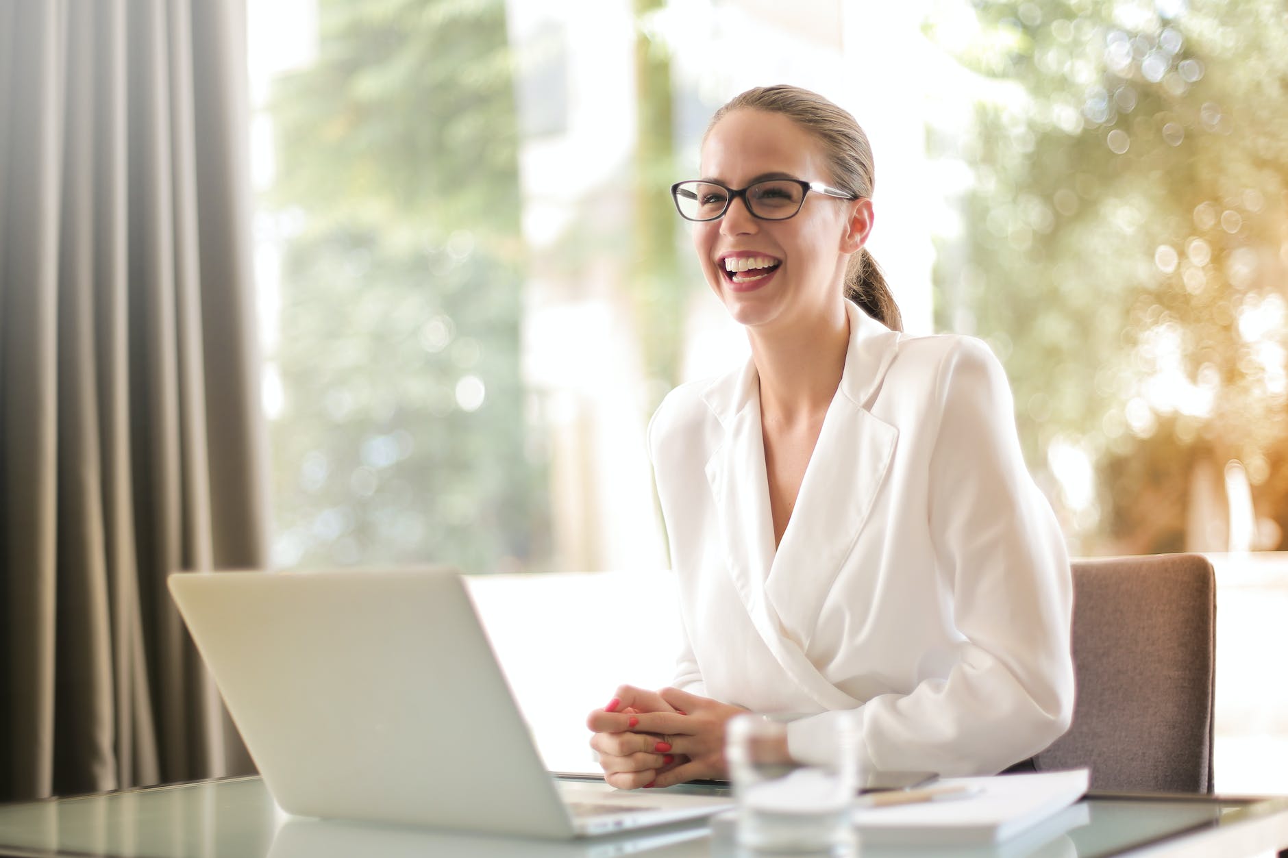 laughing businesswoman working in office with laptop, practicing mindfulness, mindfulness in relationships, mindfulness at work, mindful communication, and daily mindfulness