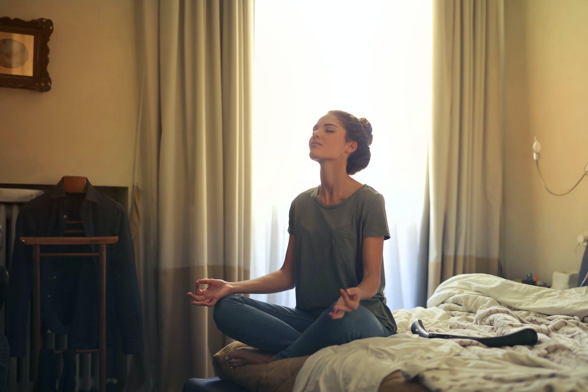 woman meditating in bedroom, considering personalized meditation, meditation goals, stress reduction, daily mindfulness, and meditation practice