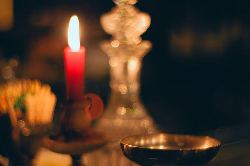 burning candle near metal bowl and carafe in church