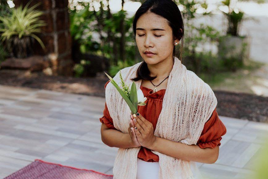 a woman praying while her eyes are closed, considering spiritual connection, meditation practice, mindfulness and intuition, connect with higher self, and meditation for inner peace