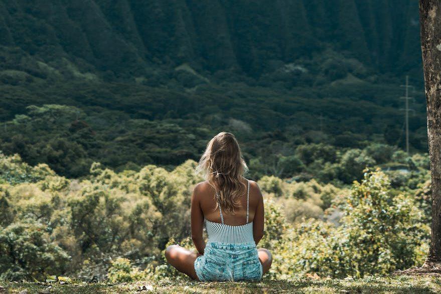 unrecognizable female meditating on grass in highlands on sunny day, exploring meditation style, personalized meditation, traditional meditation, mindfulness habits, and mind-body connection