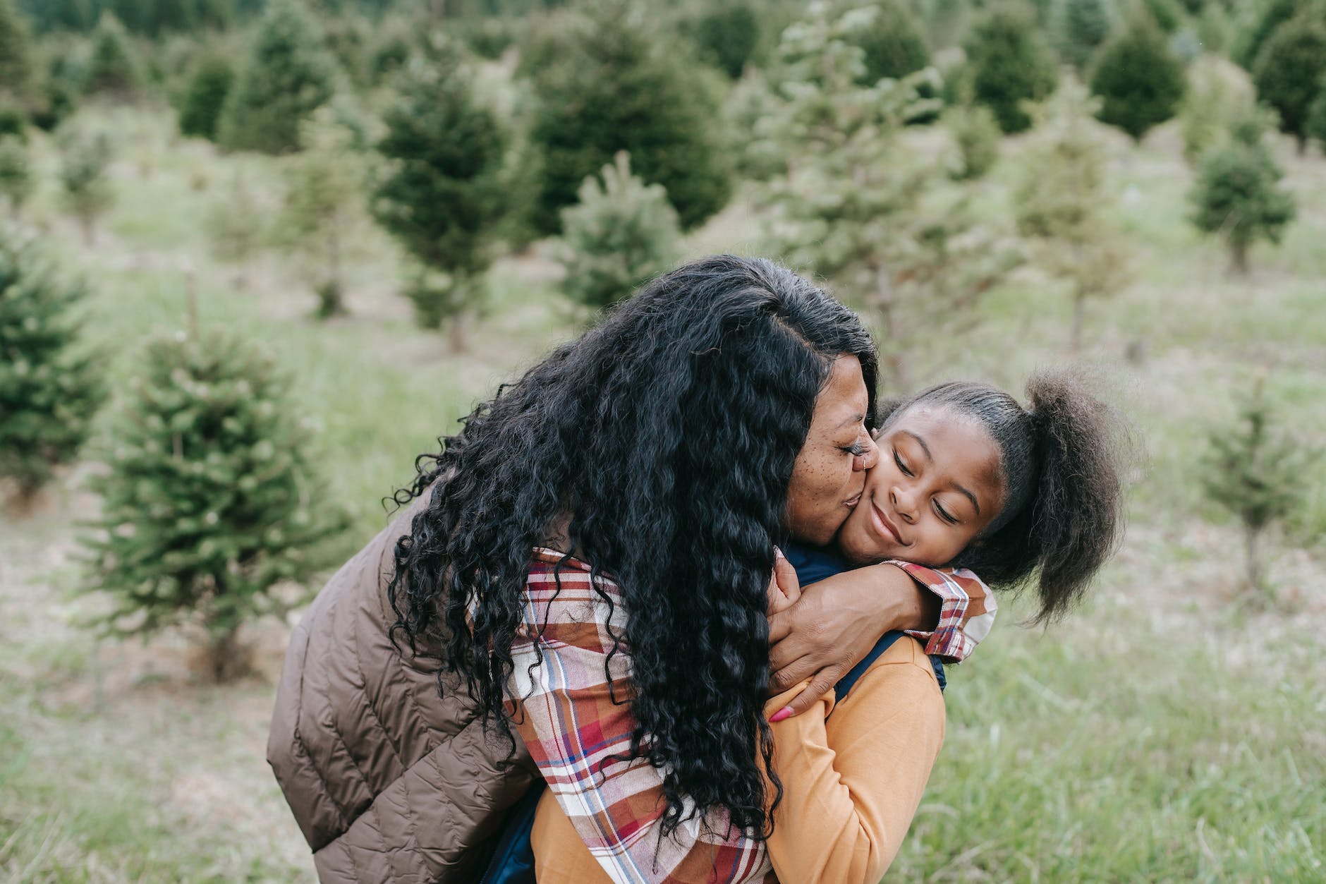 happy black mother embracing and kissing daughter, considering spiritual connection, meditation practice, mindfulness and intuition, connect with higher self, and meditation for inner peace