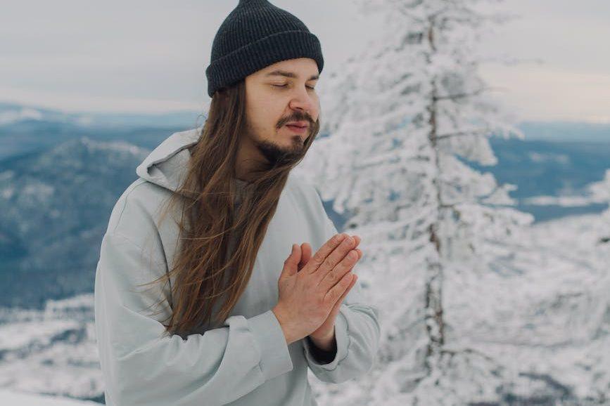 man with namaste hands sitting on snow with hapi drum, considering meditation hurdles, consistent practice, sustain mindfulness, meditation obstacles, and how to meditate consistently.