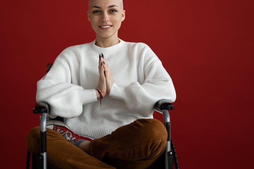 cheerful woman practicing yoga with praying hands in wheelchair, illustrating spiritual growth, meditation, awareness, ego transcendence, and intuitive wisdom
