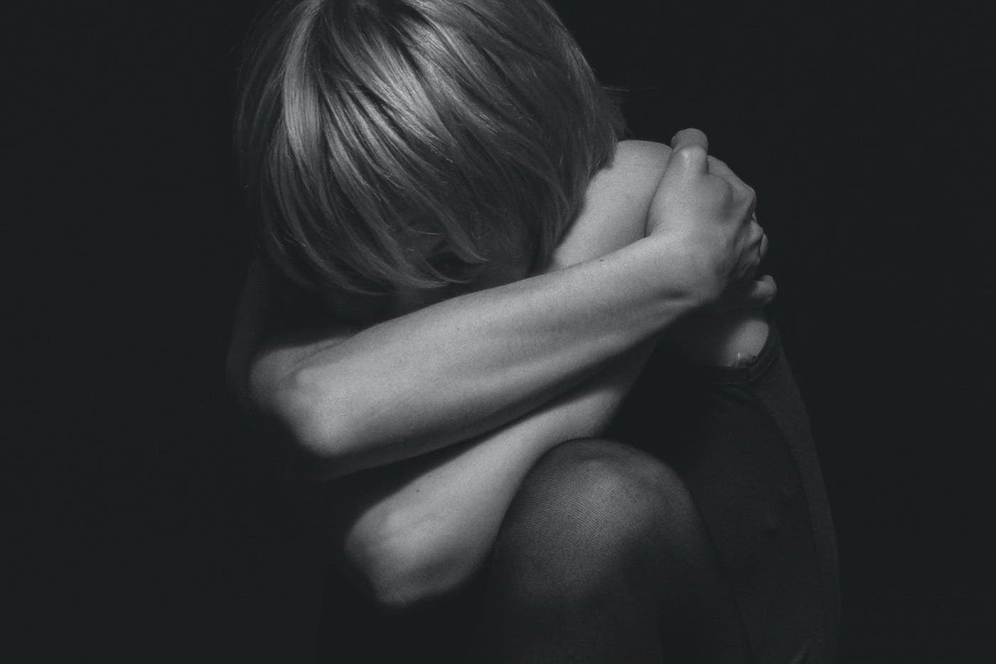 grayscale photo of a person hugging self