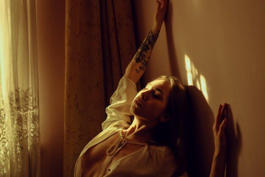 sensual model with tattoos at home in sunrays