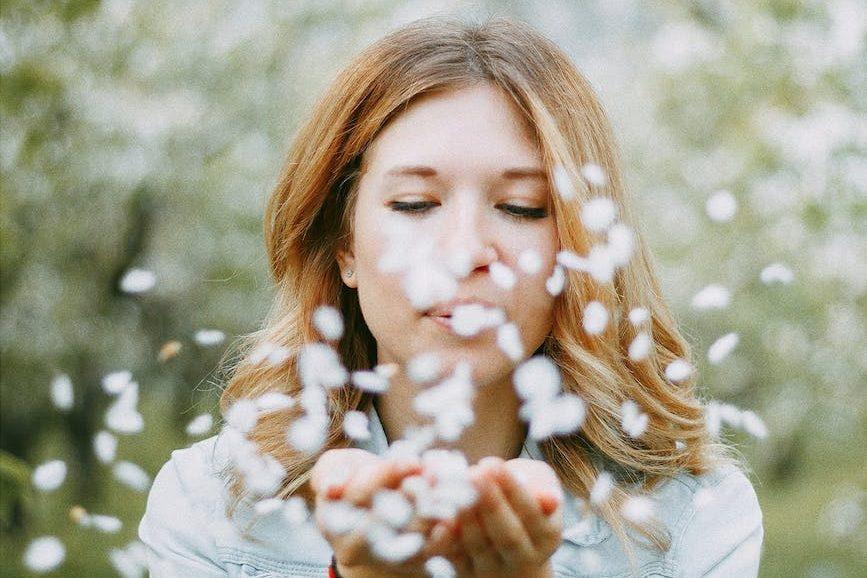 woman blowing white petals in orchard, evoking advanced meditation techniques, deep meditation practice, meditation journey, advanced mindfulness, and spiritual growth meditation