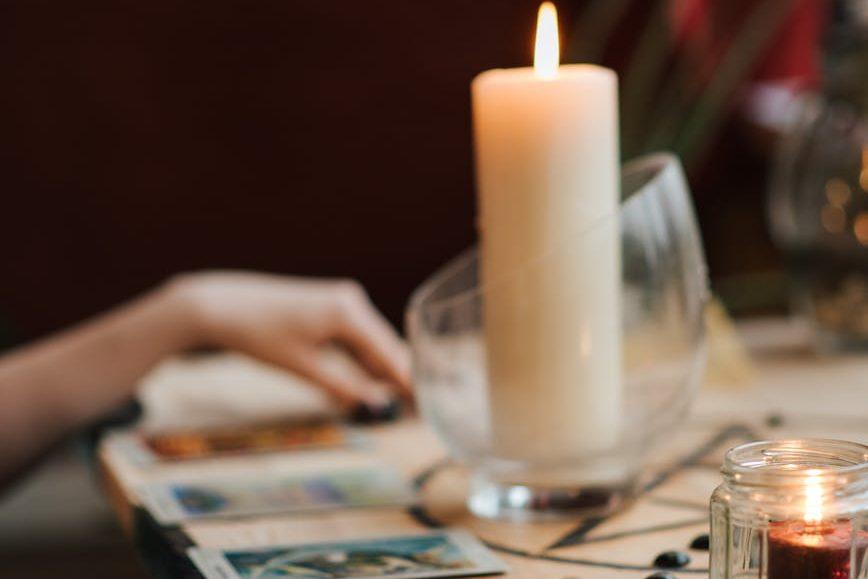 crop soothsayer reading tarot cards near luminous candles, illustrating: Mabon divination, inner wisdom, Tarot spread, harvest reflection, and the Autumn Equinox
