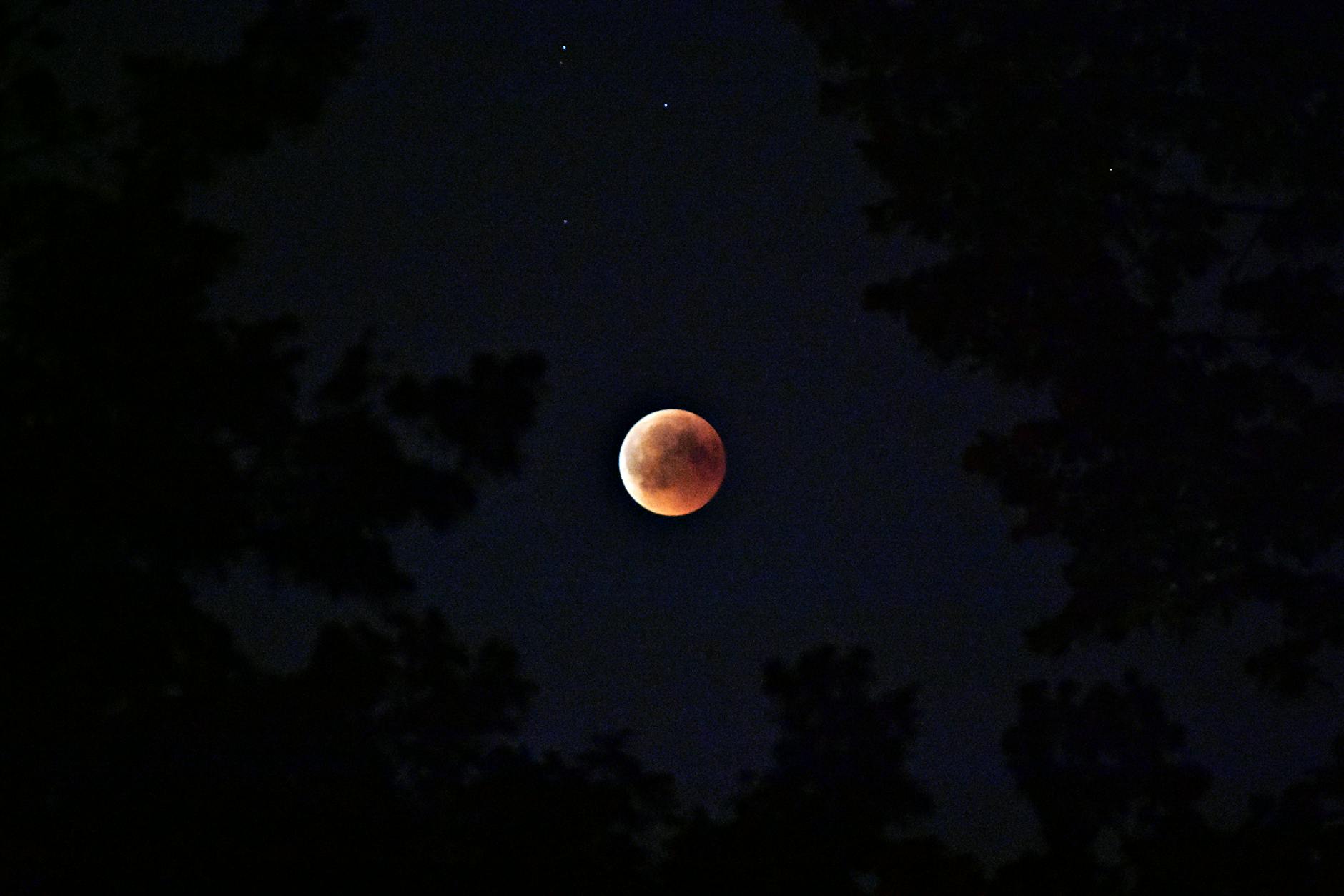 selective color photography of blood moon, illustrating: rare lunar phenomena, eclipse rituals, eclipse meaning, moon spiritual significance, and moon rituals