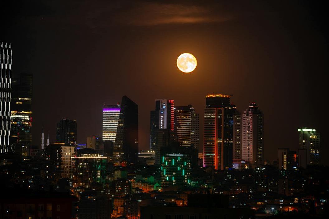 view of a city at night with full moon, showing: moon effects on humans, lunar rhythms, lunar phases and emotions, moon influence science, and moon biological rhythms