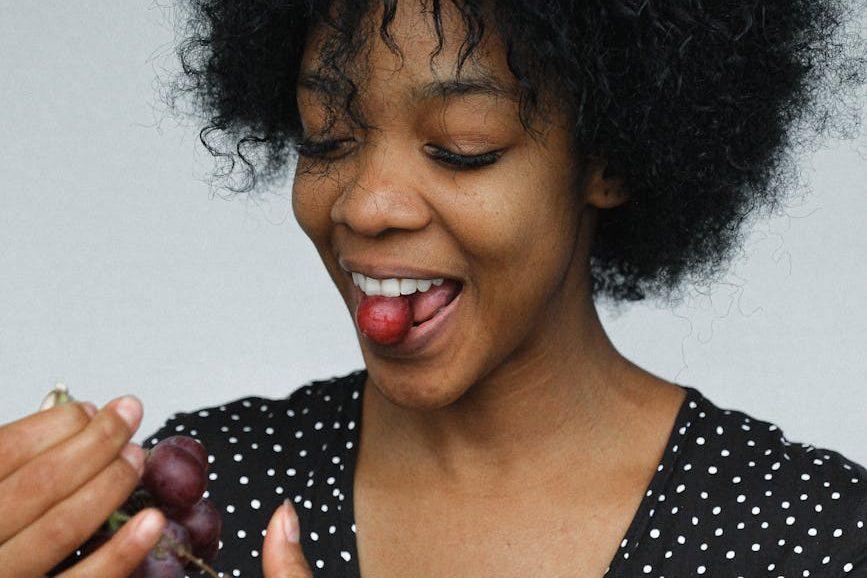playful black woman eating grapes in studio
