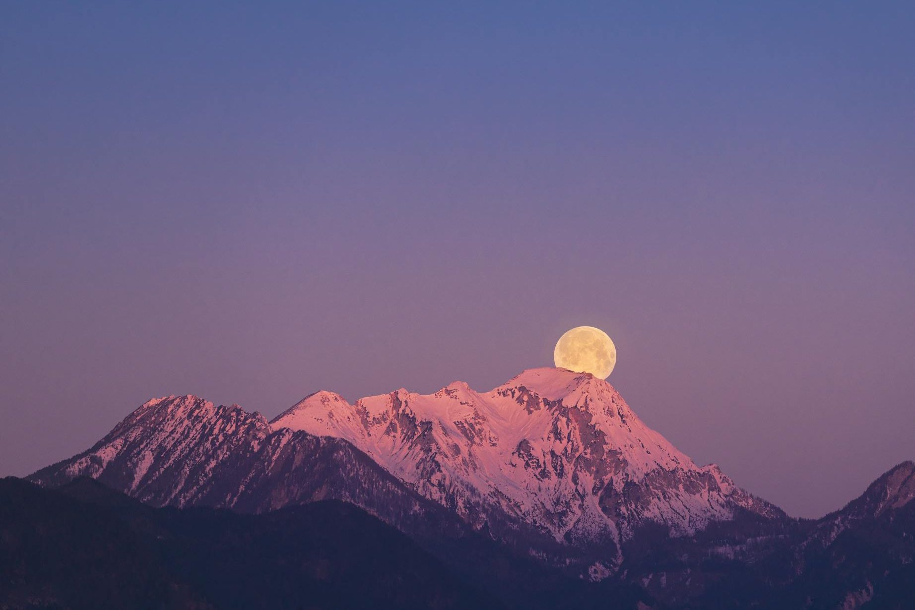 full moon above a snow covered mountain at dusk, illustrating: rare lunar phenomena, eclipse rituals, eclipse meaning, moon spiritual significance, and moon rituals