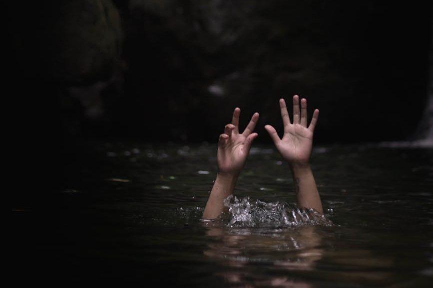 person underwater with hands up on air