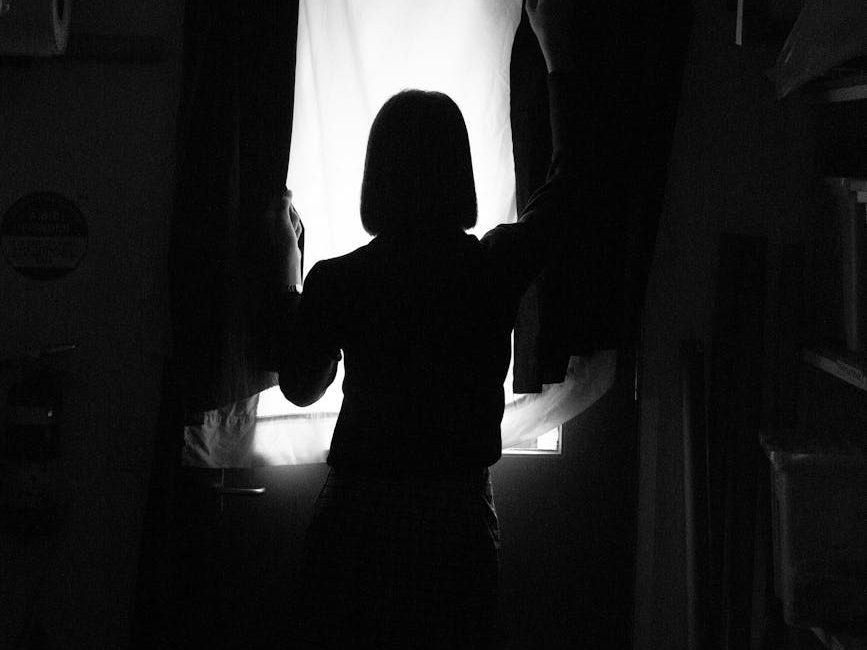 silhouette photo of person standing in front of window