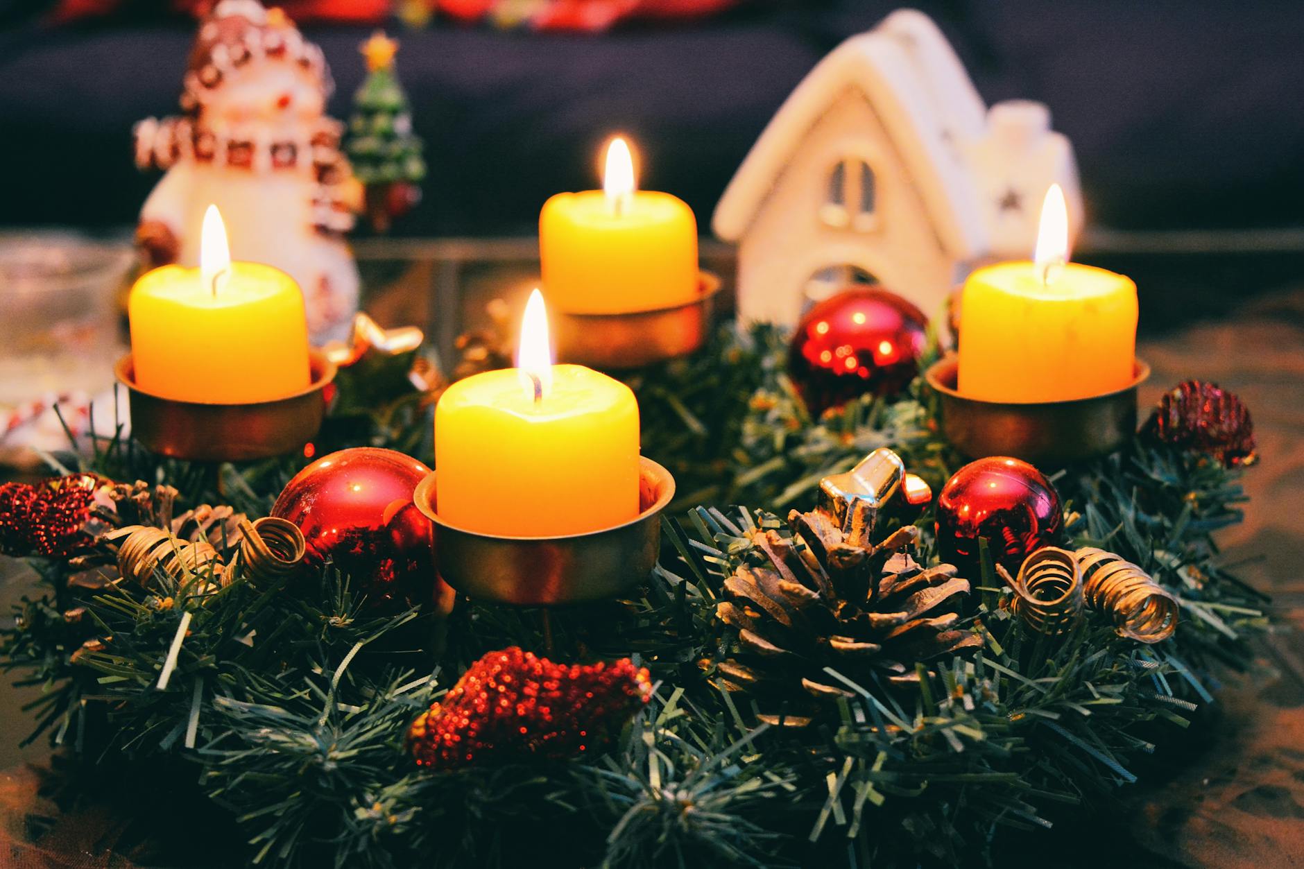 four yellow lighted candles, illustrating: the Wheel of the Year, seasonal awareness, seasonal wellbeing, living seasonally, and the Sabbats