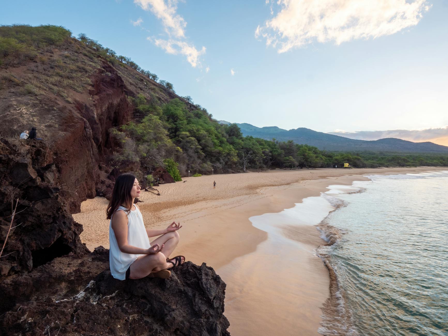 young ethnic woman meditate on empty beach, evoking: natural cycles, Wheel of the Year, seasonal traditions, Sabbats, and holidays.