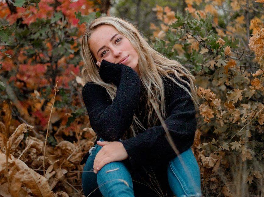 portrait of a blond woman sitting on ground in autumn