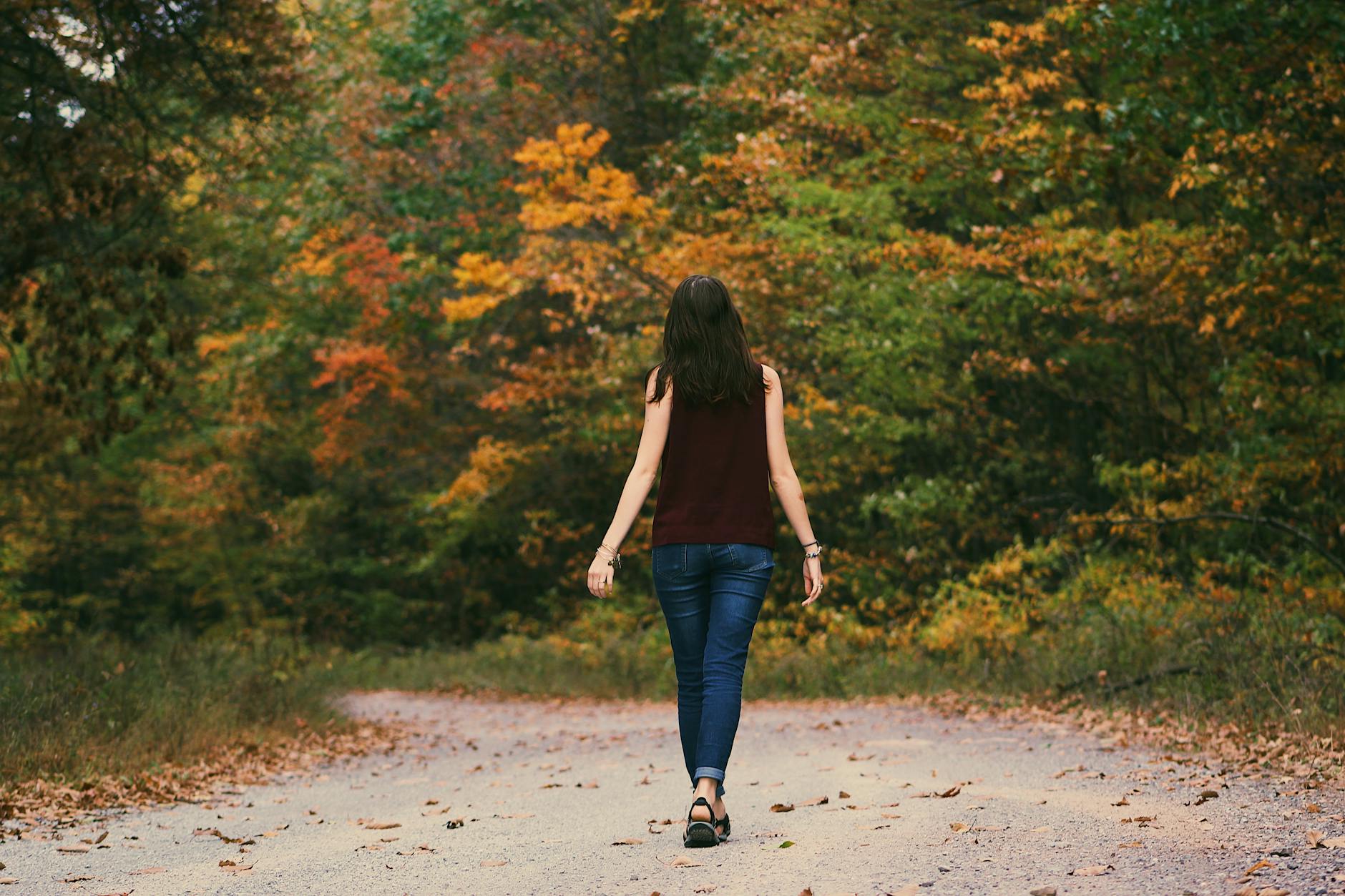 woman in brown sleeveless dress and blue jeans standing on gray path road, illustrating: holidays, rituals, holiday ritual, seasonal tradition, and traditions