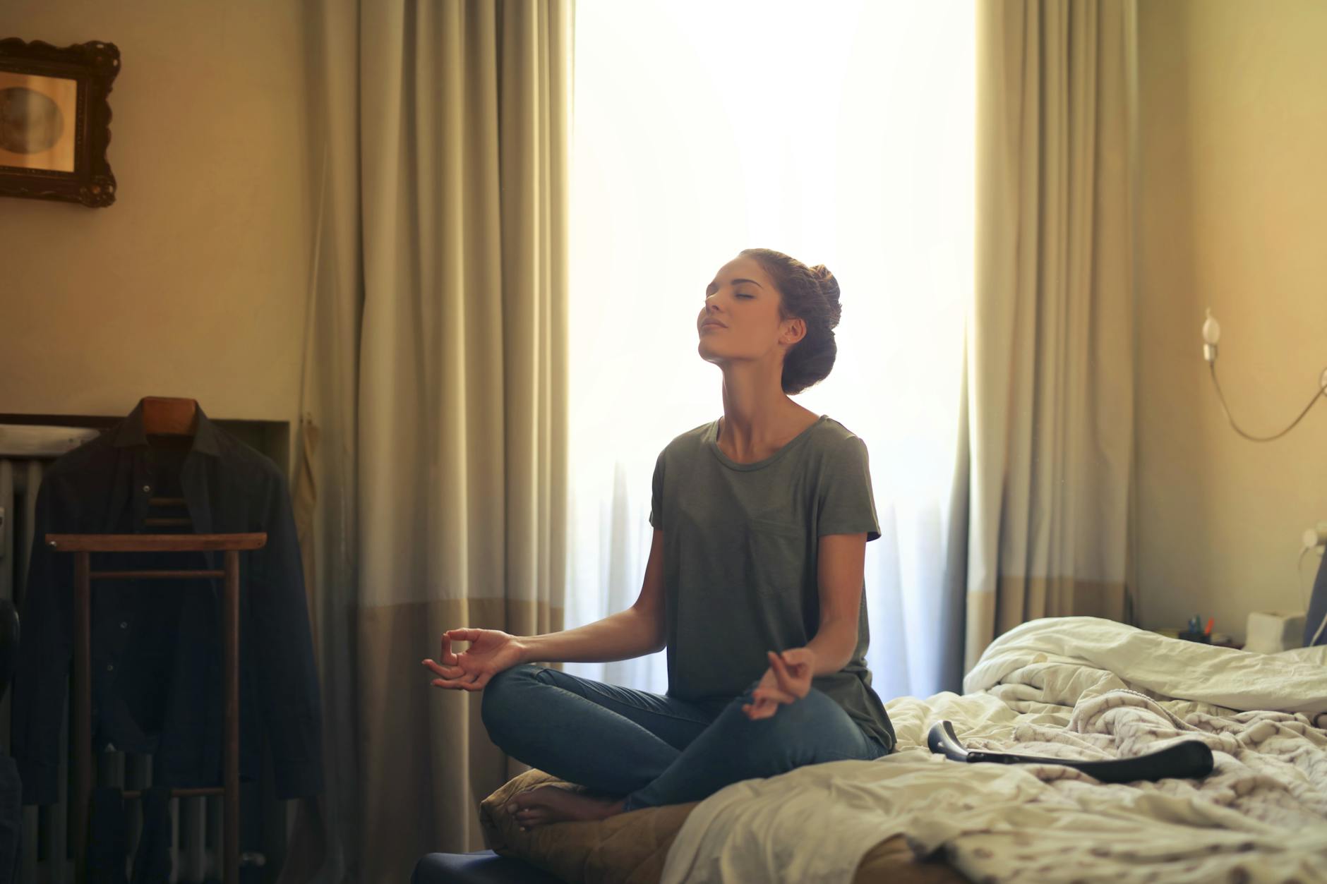 woman meditating in bedroom, evoking: real manifestation, gratitude, abundance mindset, and intentional living