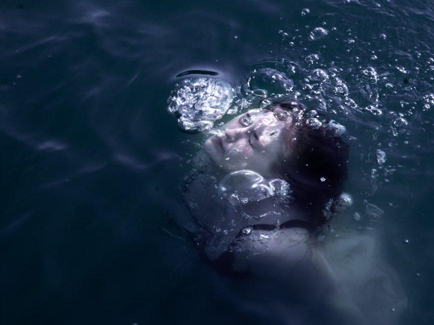 a photo of a woman swimming underwater, illustrating: Scorpio, transformation, Scorpio season, Hellenistic astrology, and renewal