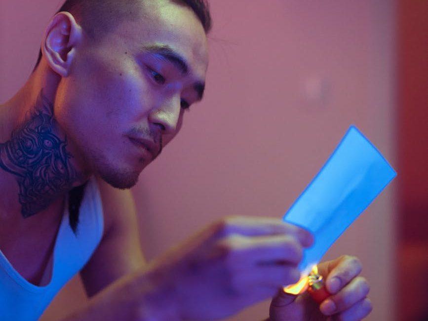 a tattooed man burning a paper