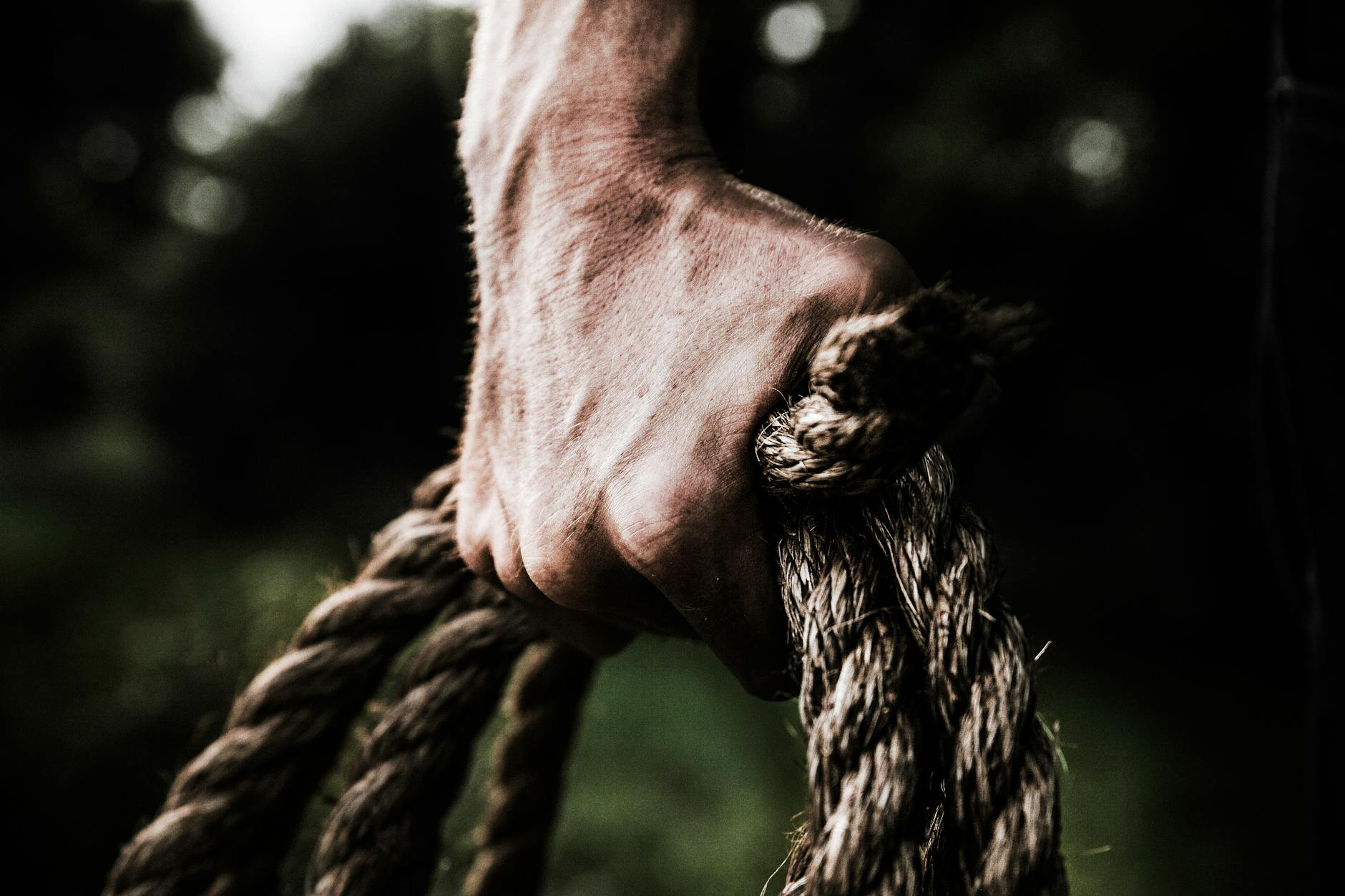 man holding brown rope, illustrating: alchemy, transforming hardship, gratitude, abundance, and resilience 