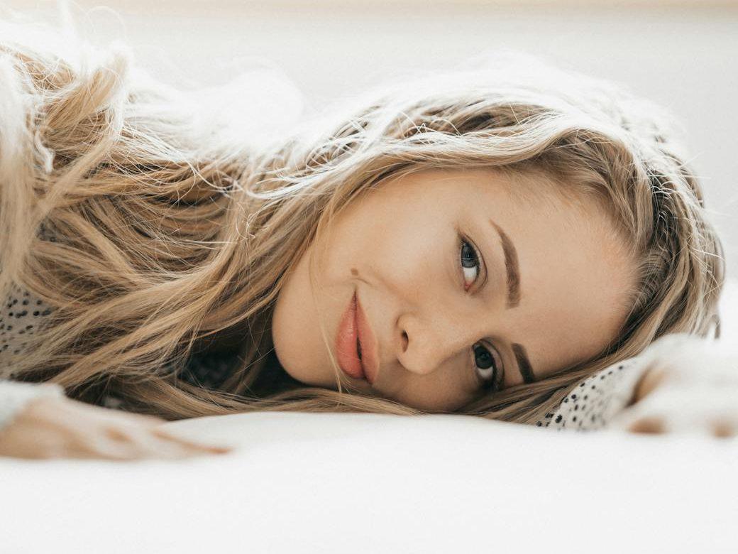 young woman lying on a bed and smiling