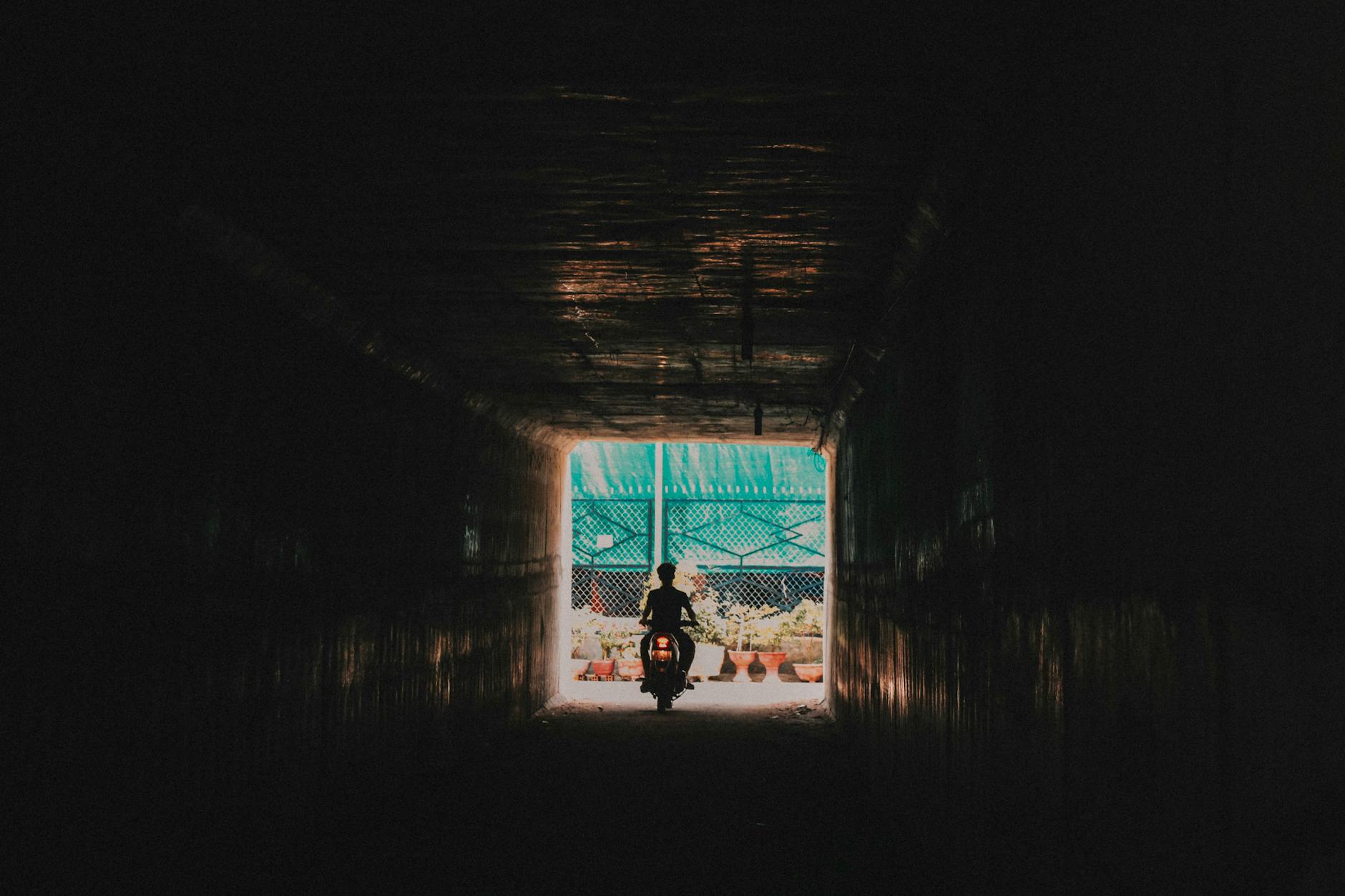 person riding a motorcycle going out from the tunnel, illustrating: alchemy, transforming hardship, gratitude, abundance, and resilience 