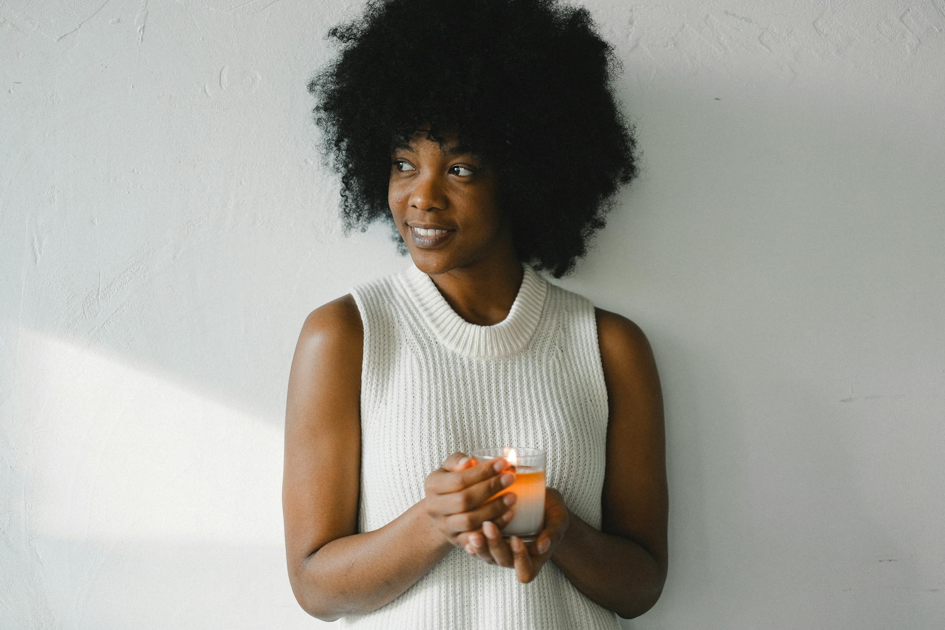 smiling woman with burning candle at home
