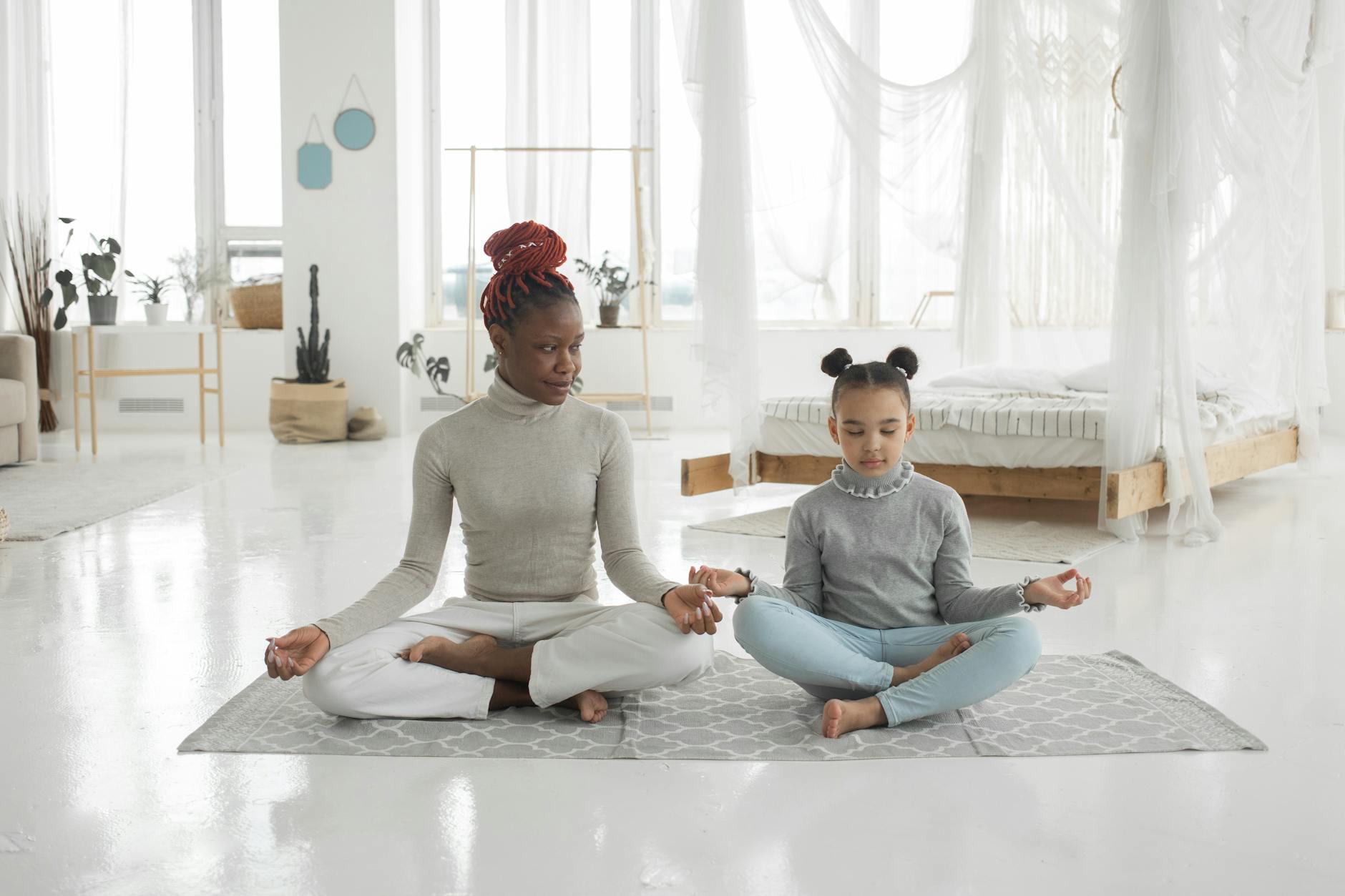 young black mother practicing yoga with daughter in light bedroom, evoking: Thanksgiving, gratitude, cultural traditions, global, and giving thanks