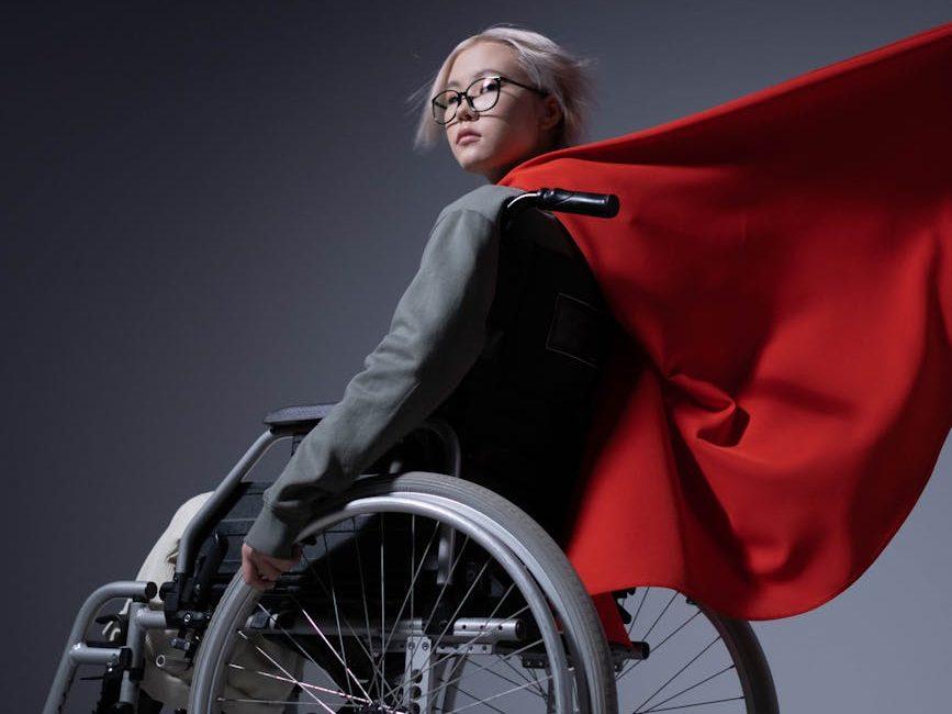 teenage girl sitting on wheelchair with a cape