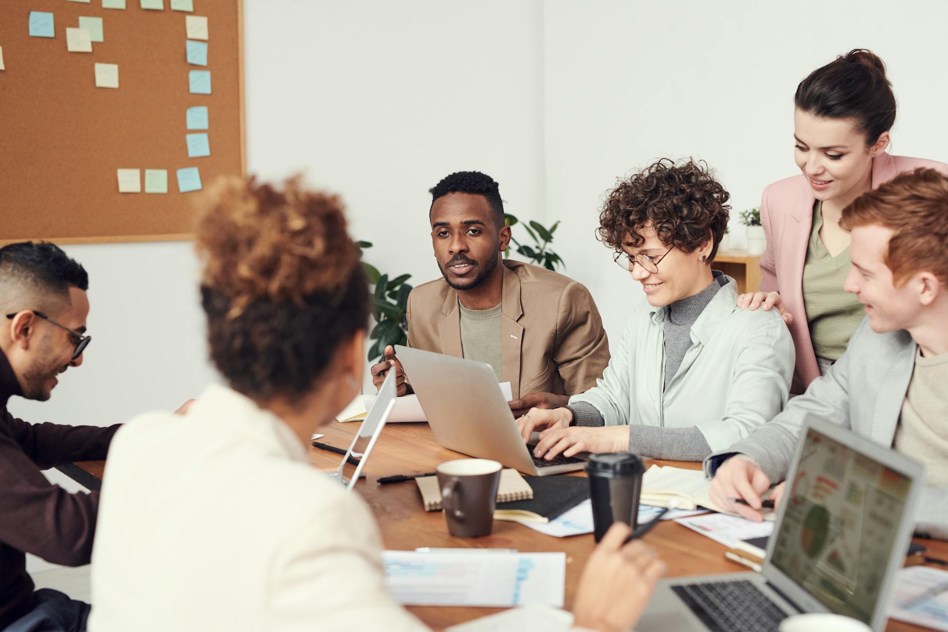 man wearing brown suit jacket, smiling in a work meeting, illustrating the self-empowerment of mindfulness techniques 