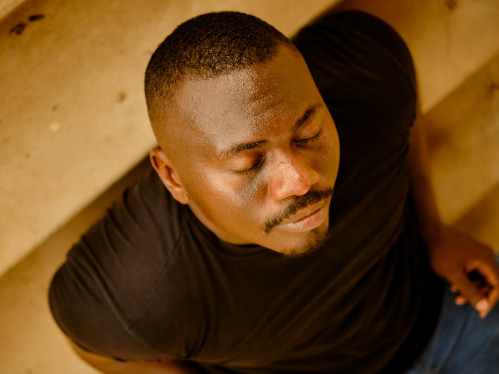 man relaxing with eyes closed on stairs, practicing deep breathing exercises for stress relief, calm and relaxation