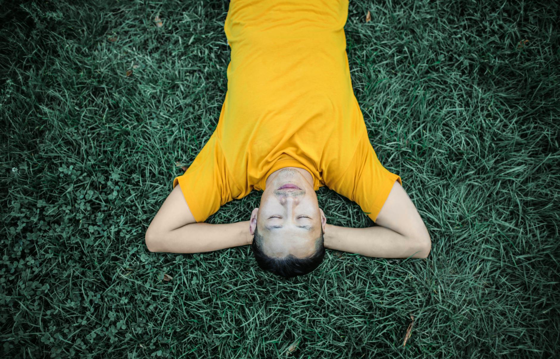 photo of person laying on grass field, illustrating mindfulness techniques for emotional resilience