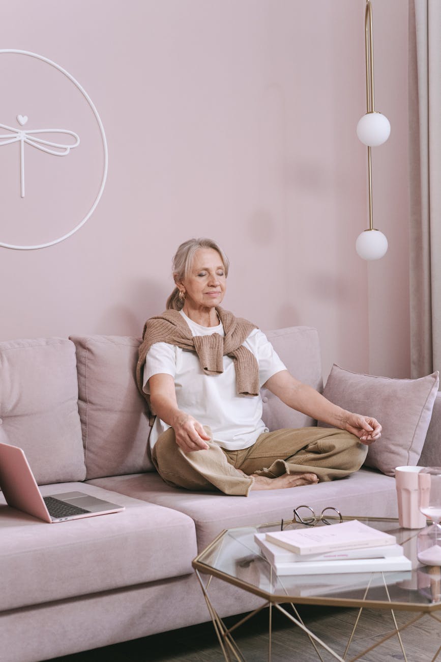 a woman sitting on the couch practicing deep breathing and other breathing exercises for stress relief, calm and relaxation