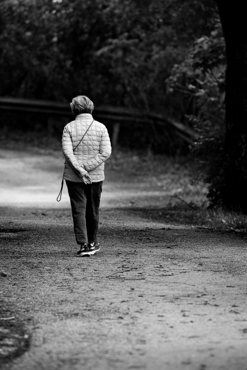 senior woman walking in peaceful park trail, enjoying walking as a benefit of digital minimalism and mindful consumption