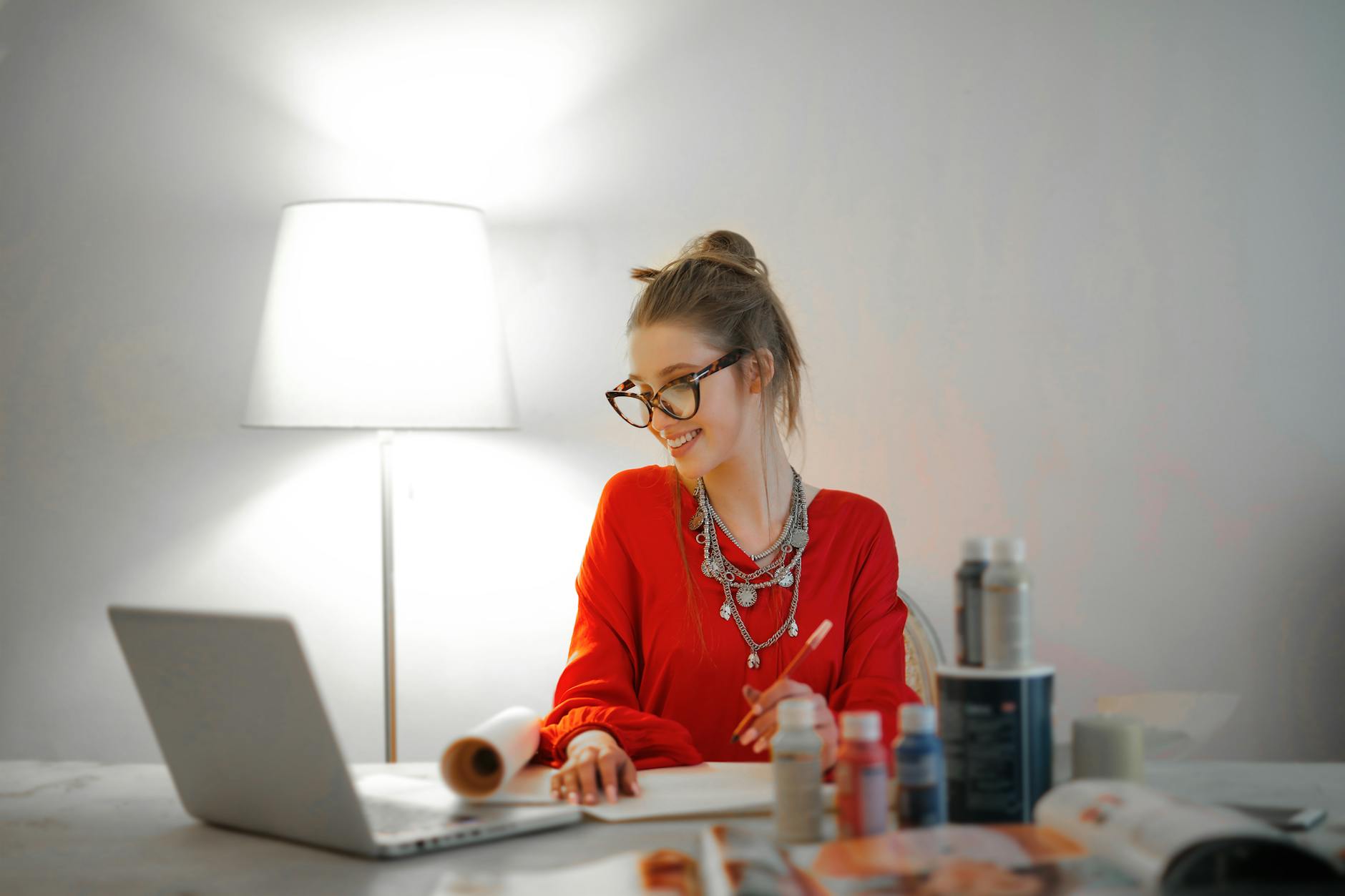 woman in red long sleeve shirt looking at her laptop, smiling because instead of a dopamine detox she practices dopamine management